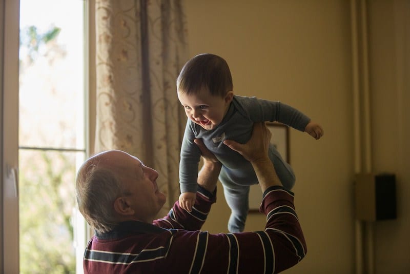 Un senior qui porte un bébé heureux