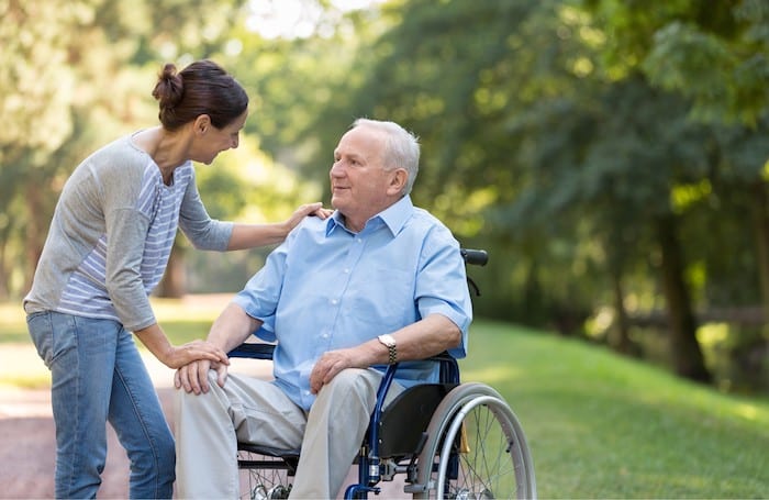 Une auxiliaire de vie qui prend soin d'une personne âgée en fauteuil roulant