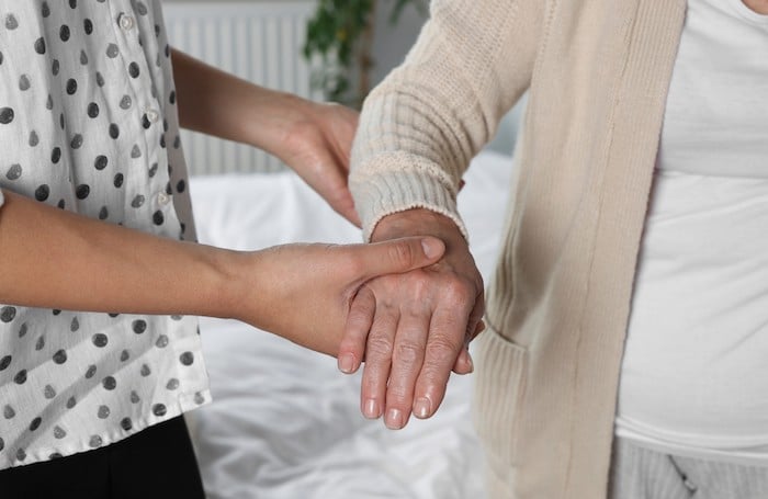 Une auxiliaire de vie qui tient la main d'une personne âgée